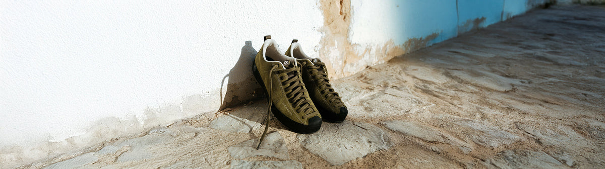 Scarpa Freizeitschuhe für Herren aus Veloursleder in Oliv an einer weißen Hauswand