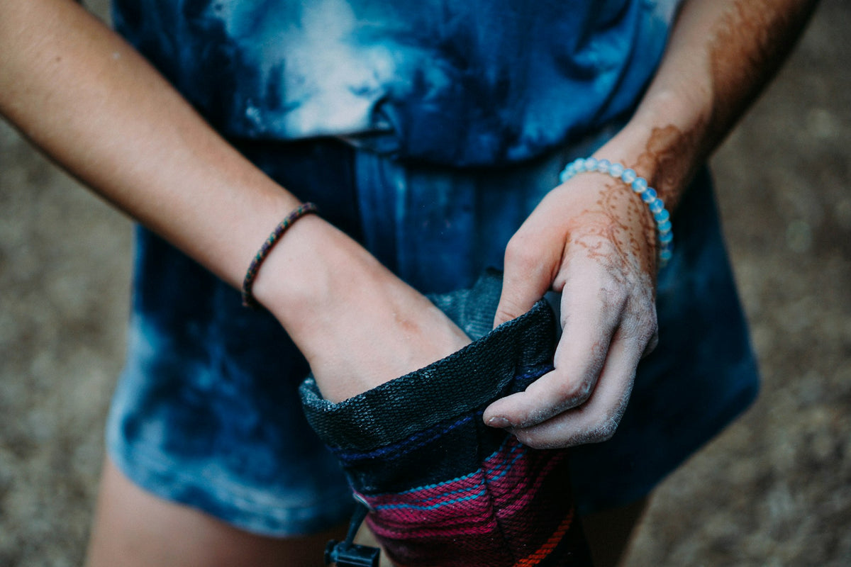 Hand greift beim Klettern in einen Chalkbag am Hüftgurt