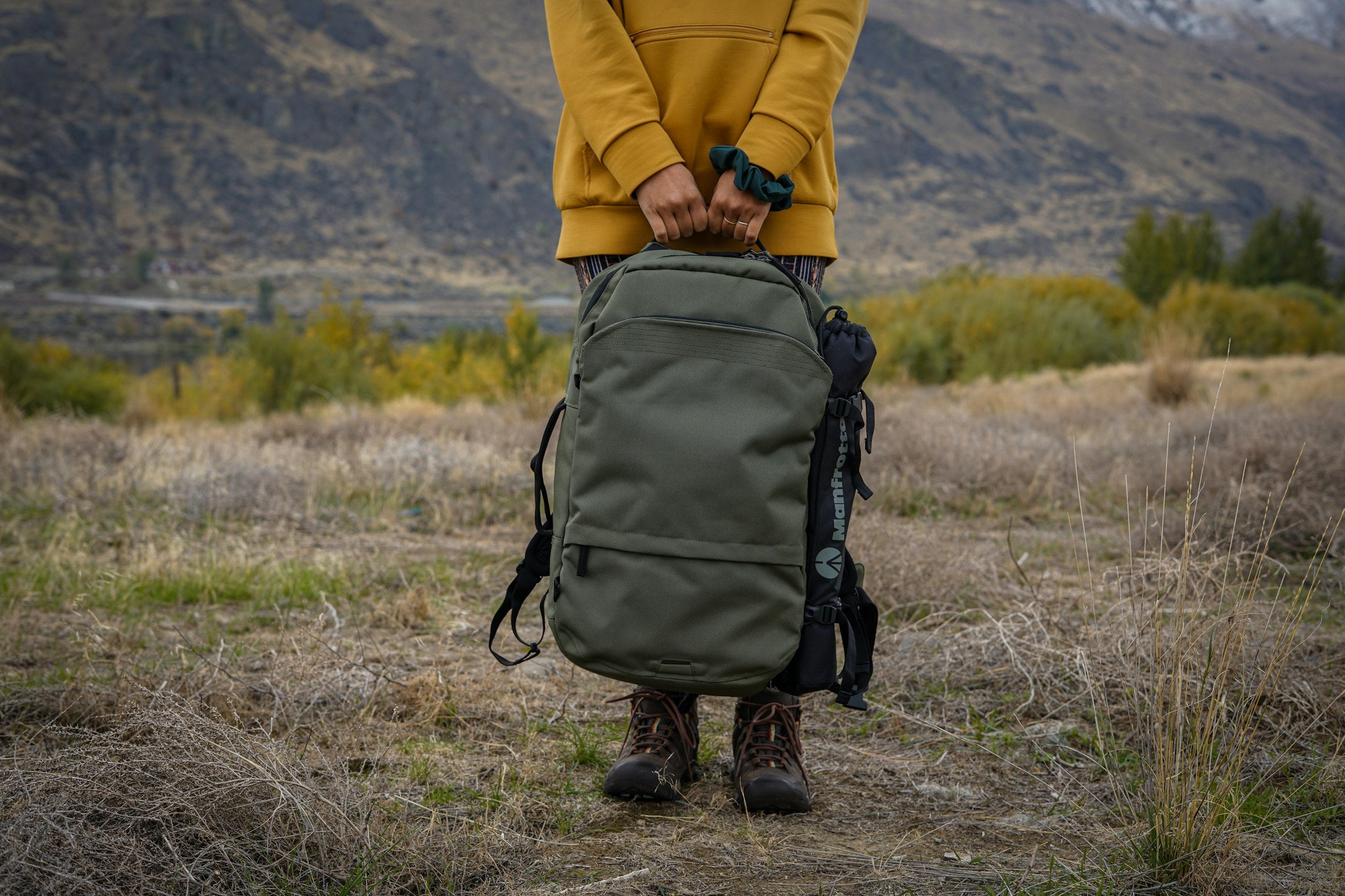 Reisende in gelber Jacke hält einen großen Reiserucksack – Ausrüstung für Work and Travel