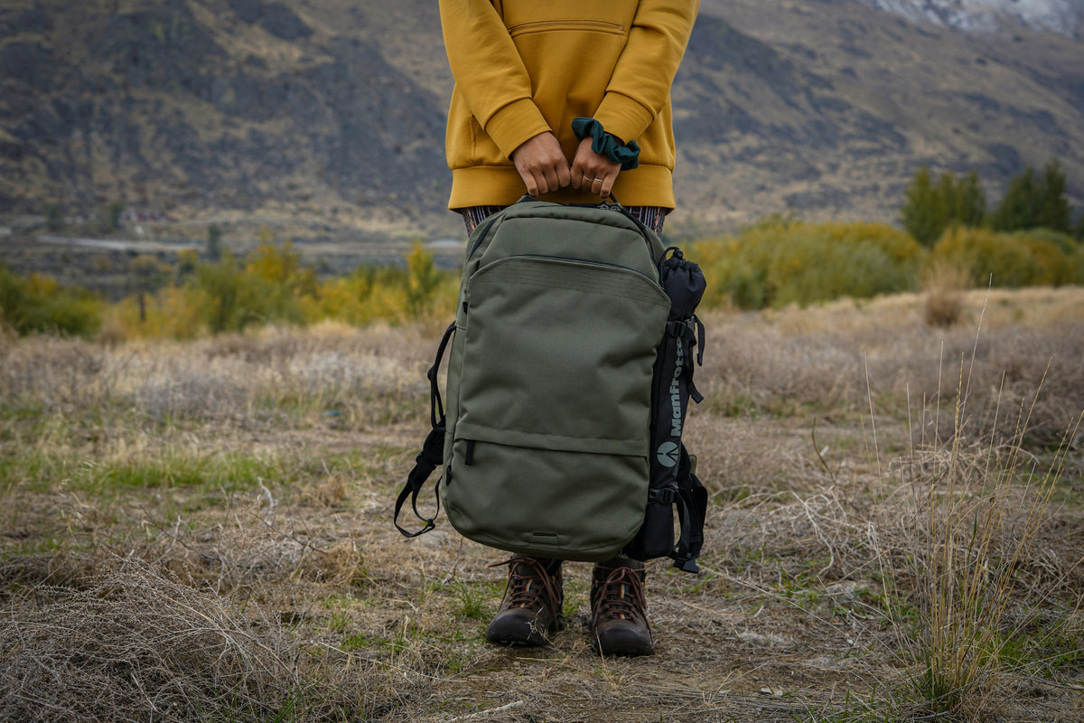 Reisende in gelber Jacke hält einen großen Reiserucksack – Ausrüstung für Work and Travel