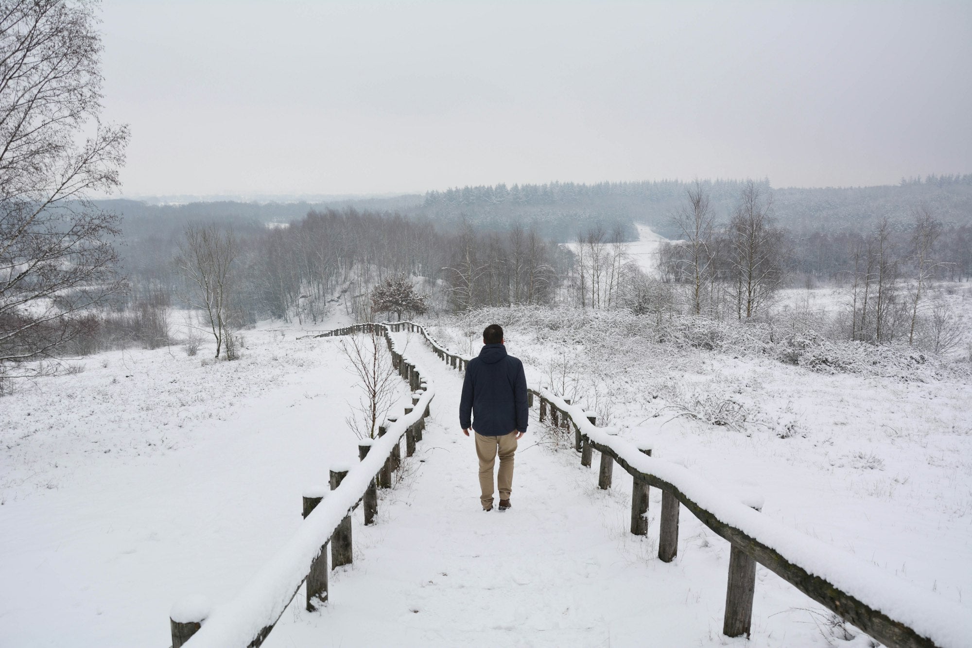 Wanderer auf einem verschneiten Holzbohlenweg im Winter
