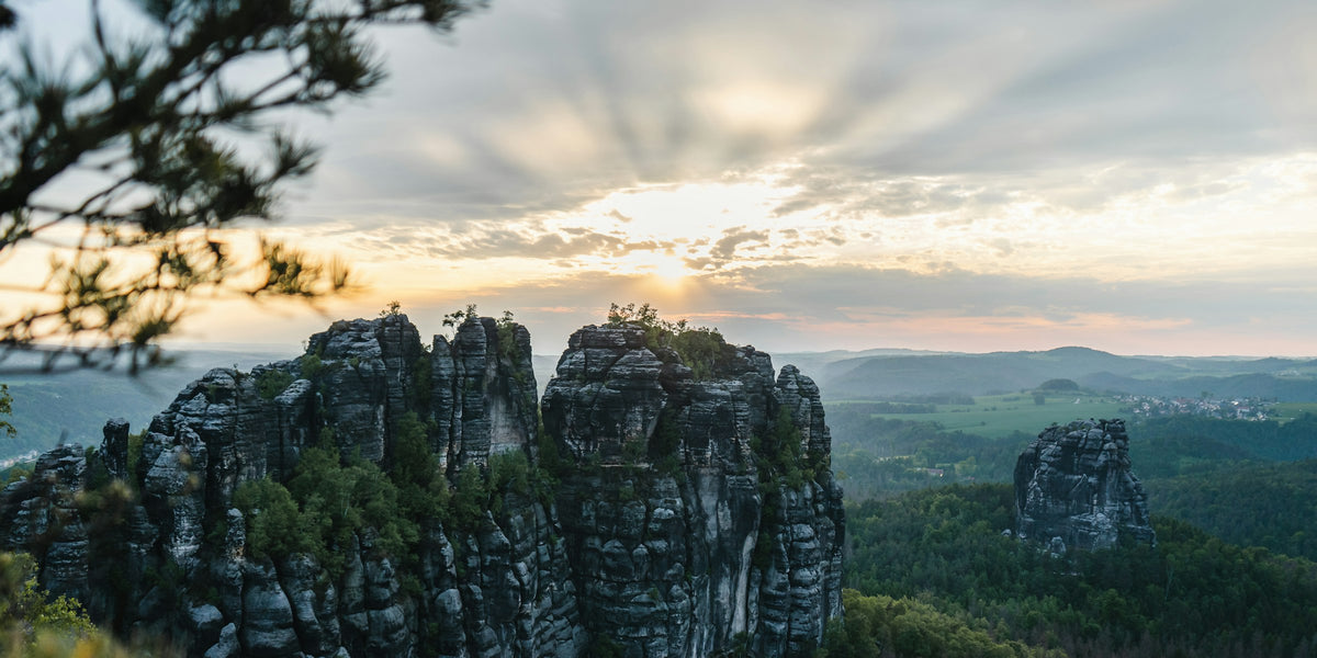 Sandsteinfelsen der Schrammsteine über bewaldeten Tälern in der Abendsonne