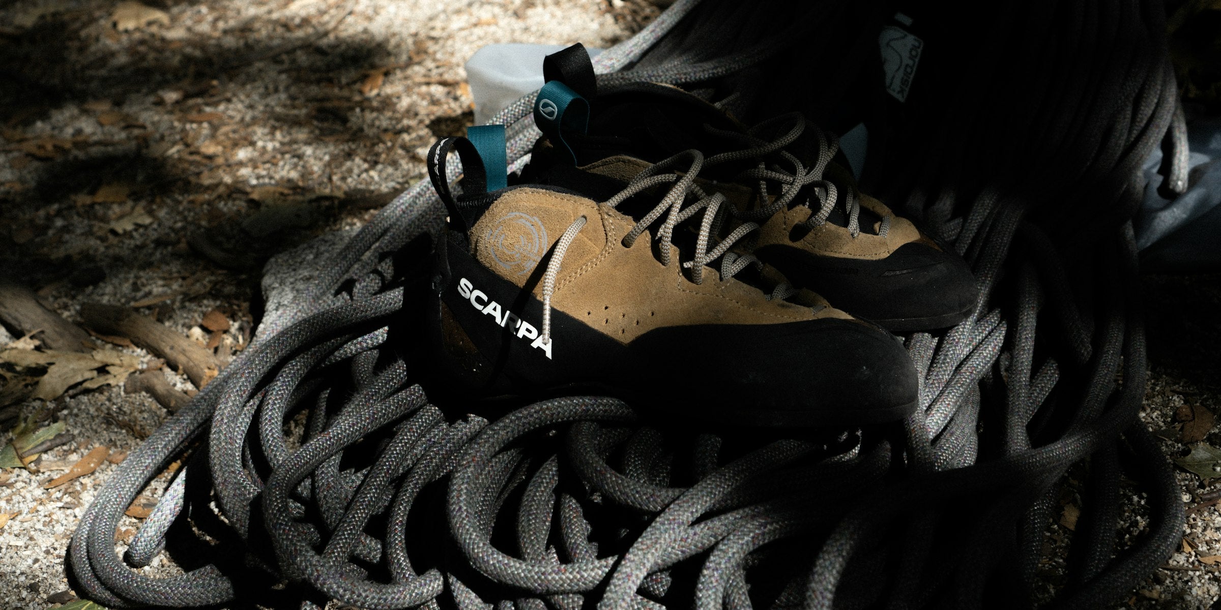 Kletterschuhe liegen auf einem aufgeschossenen Kletterseil