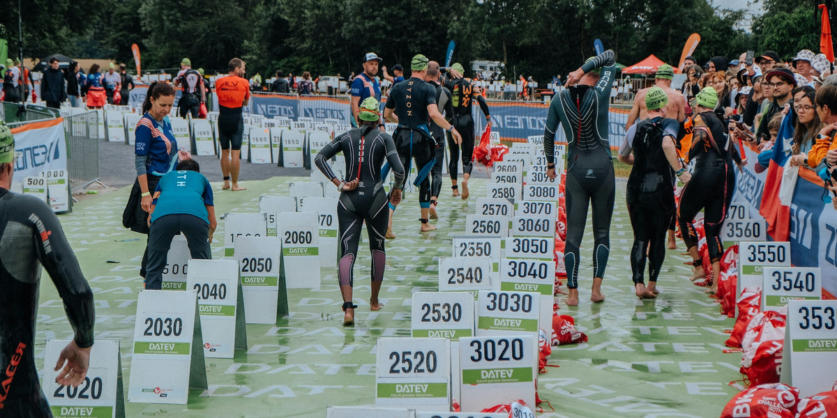 Triathleten in Neoprenanzügen auf dem Weg vom Schwimmausstieg zur Wechselzone