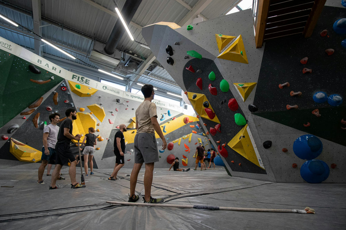 Boulderhalle mit bunten Griffen und Kletternden an der Wand
