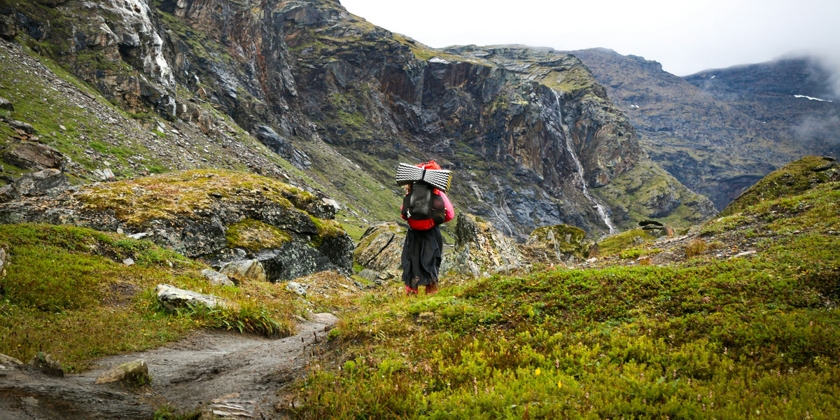 Wanderer mit großem Trekkingrucksack auf einem Pfad durch ein felsiges Tal bei Abisko
