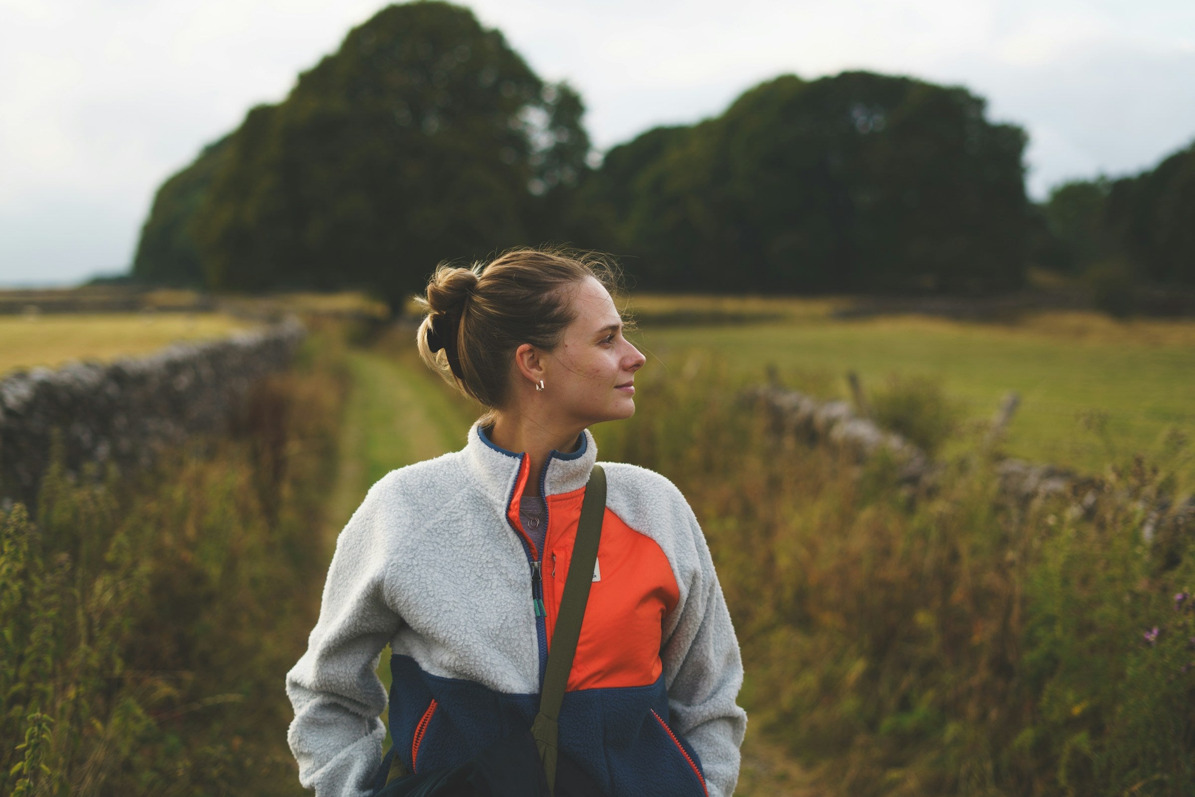 Frau in Fleecejacke auf einem Feldweg im Herbst