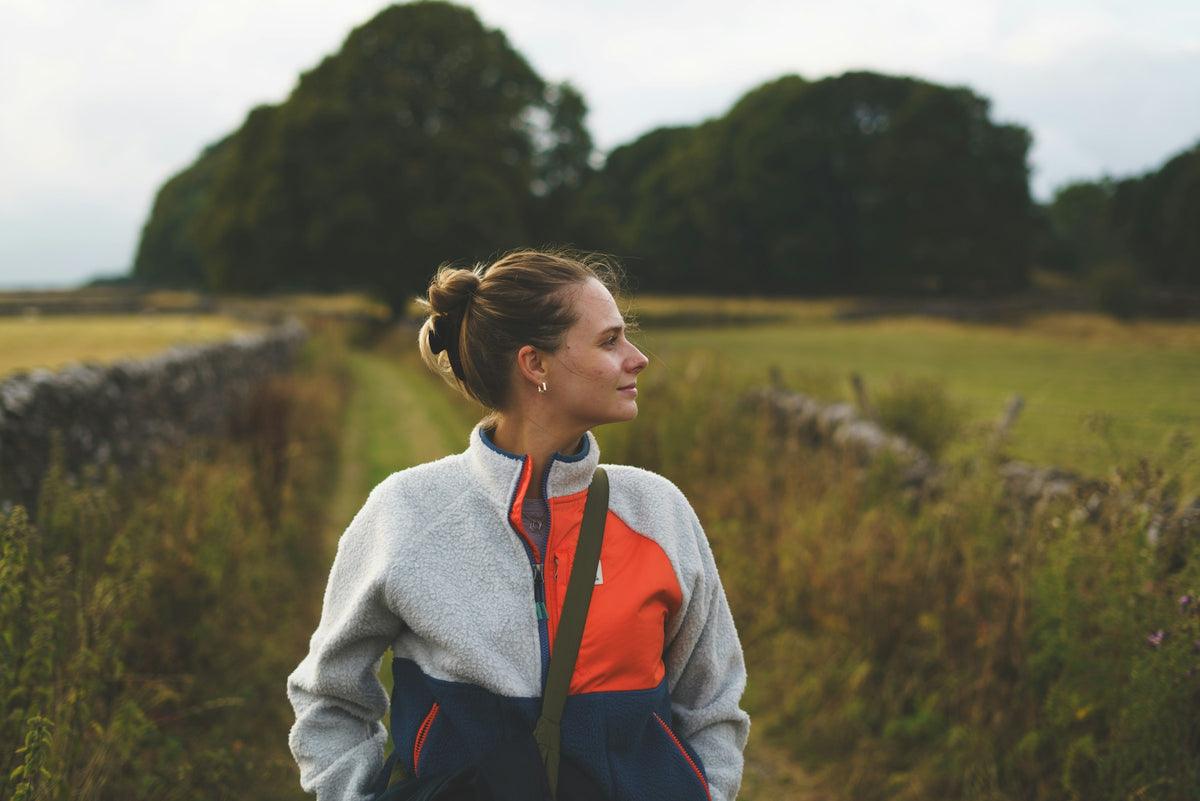 Frau in Fleecejacke auf einem Feldweg im Herbst